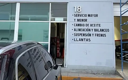 Entrada del local 18 en Av. Pirineos 500, con la lista de servicios en la fachada